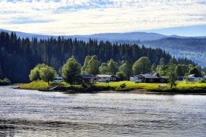 Green and idyllic Korgen Camping seen from the other side of the river Røssåga that passes right next to the camping. 