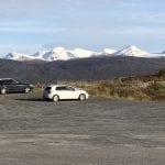 Two cars parked in the parking space at Korgfjellet with a great view of the Okstindan mountains in the horizon.