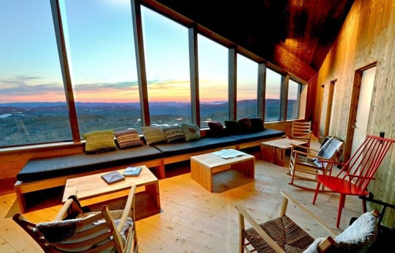 Living room at Rabothytta with a view over a beautiful and colorful sunset seen through the big panorama windows.