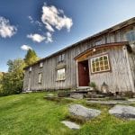The main building at Inderdalen Farm, a beautiful, old, grey and wooden building with a path of stones leading up to it.