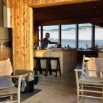 Host making waffles in the kitchen at Rabothytta with view of glacier trough the panorama windows in the background.