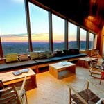Living room at Rabothytta with a view over a beautiful and colorful sunset seen through the big panorama windows.