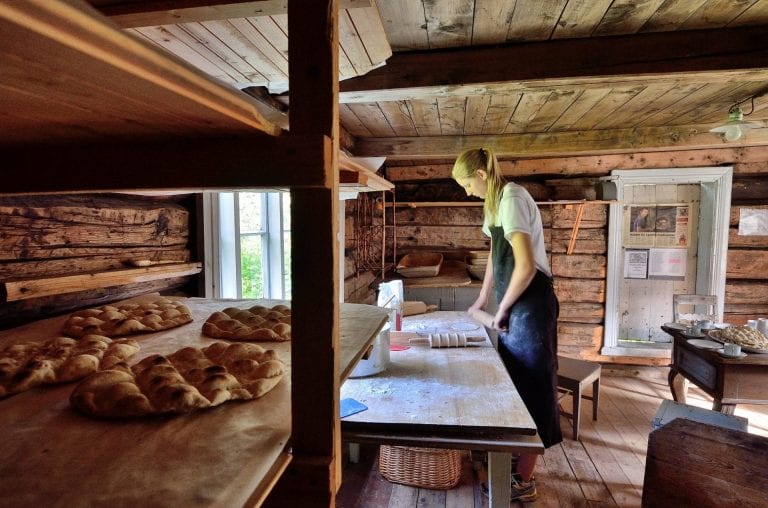Young woman baking the local bread, “kamkake”, inside an old and wooden baking house.