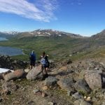 Hikers walking down from Oksskolten in the summer with a nice view over the lake, Kjennsvatnet and mountains in the horizon.