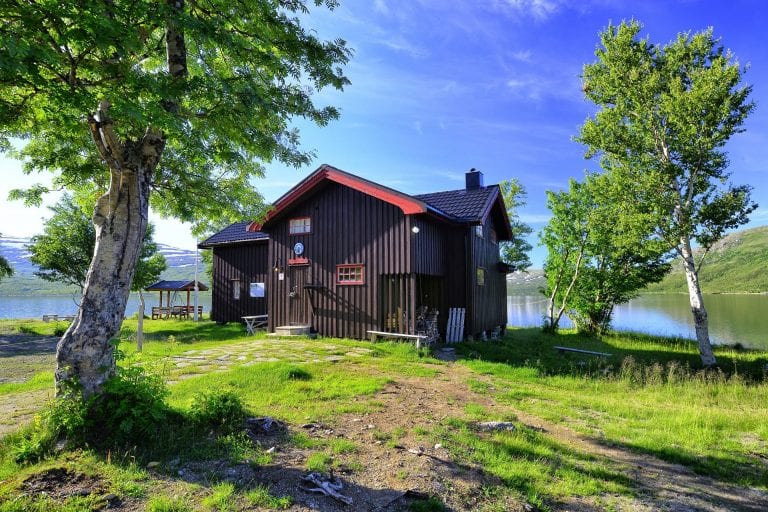 Picture of the cabin, Kjenvasshytta, with the lake right behind it and beautiful mountain surroundings.