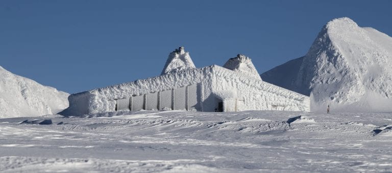 A snow-covered cabin in the mountains, “Rabothytta”, surrounded by a white landscape in all directions.