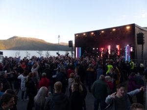 People dancing in front of the stage at “Båt of fjord”-festival, located right next to fjord and mountains at Hemnesberget.