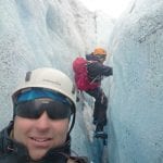 Selfie of a happy Frank from Rivojen Adventure and his friend, climbing a crack in the ice blue glacier.