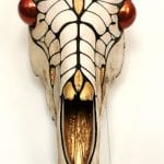 A beautifully decorated animal head in gold, shining red and black colors, created by artist, Yvonne.