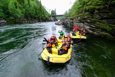 Two yellow rafting boats on the river filled with lots of excited and happy people.