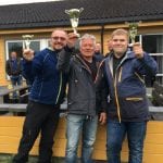 Three happy men holding their own golden trophy after having won the Word Championship in “Skøthella” in Korgen.