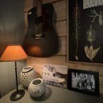 Cozy corner with a lamp, a guitar, an old school poster and old pictures.